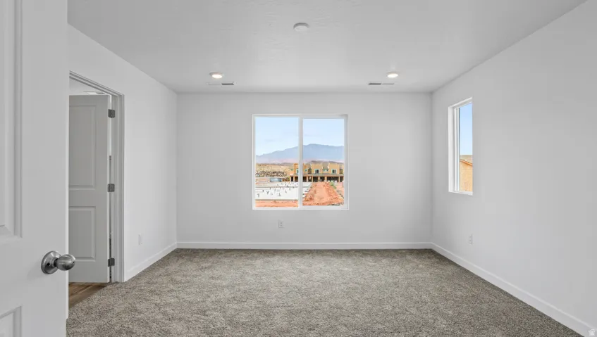 Spacious room featuring neutral carpeting, recessed lighting, white walls, and multiple windows