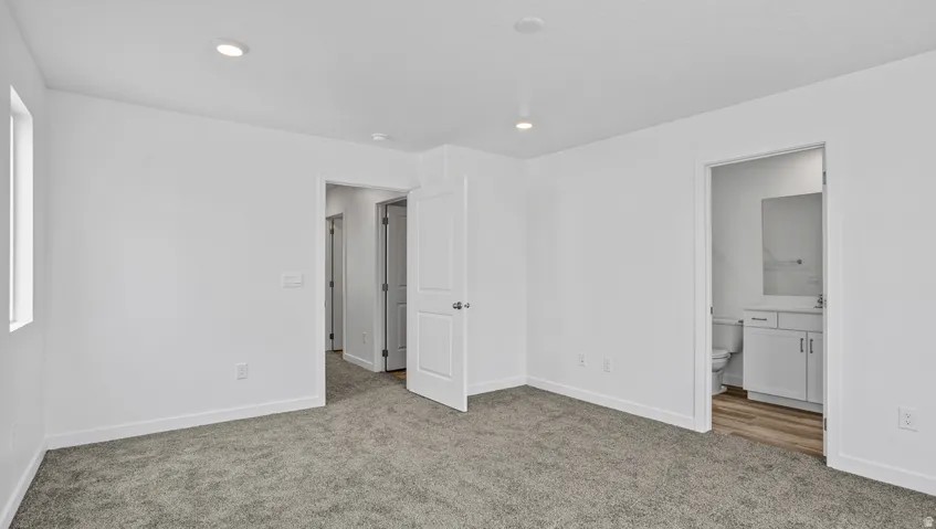 Spacious room featuring neutral carpeting, recessed lighting, and crisp white walls
