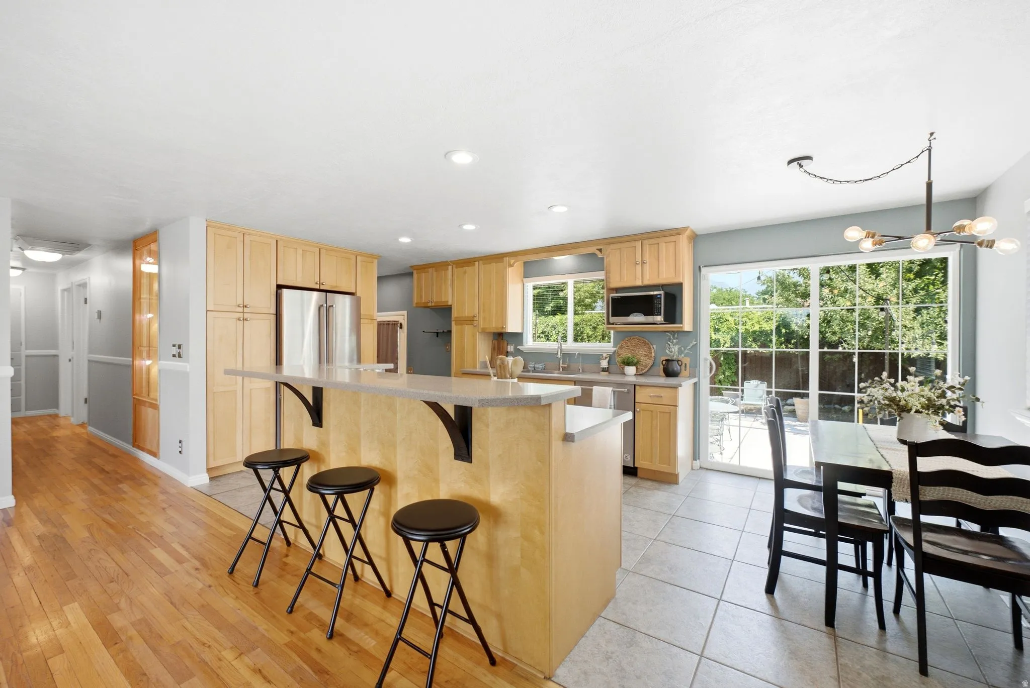 Spacious kitchen featuring light wood cabinetry, stone countertops, and stainless steel appliances