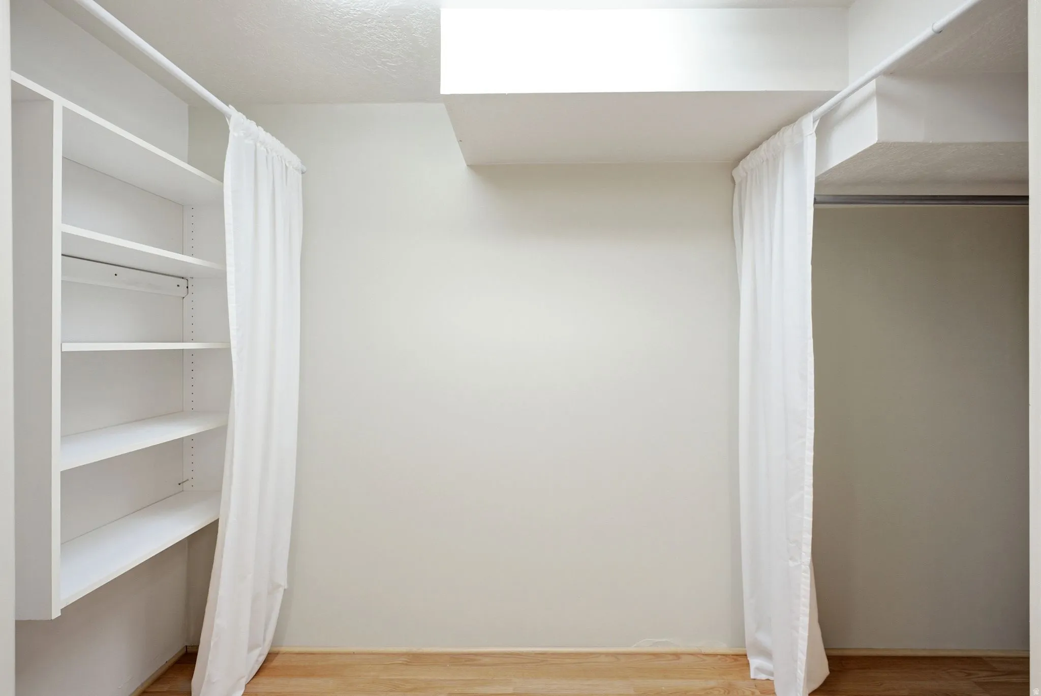 White storage shelving and hanging rod with light-colored flooring