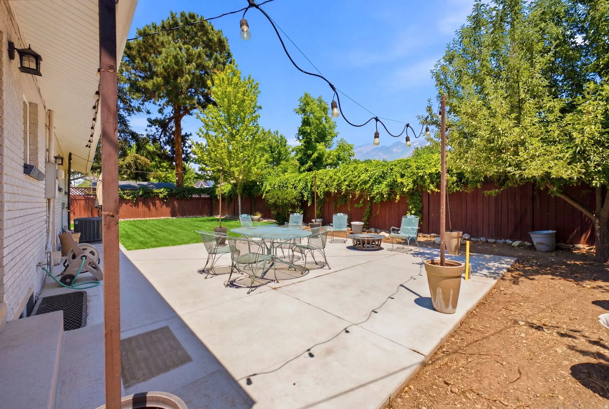 Expansive concrete patio area featuring string lighting and a fire pit