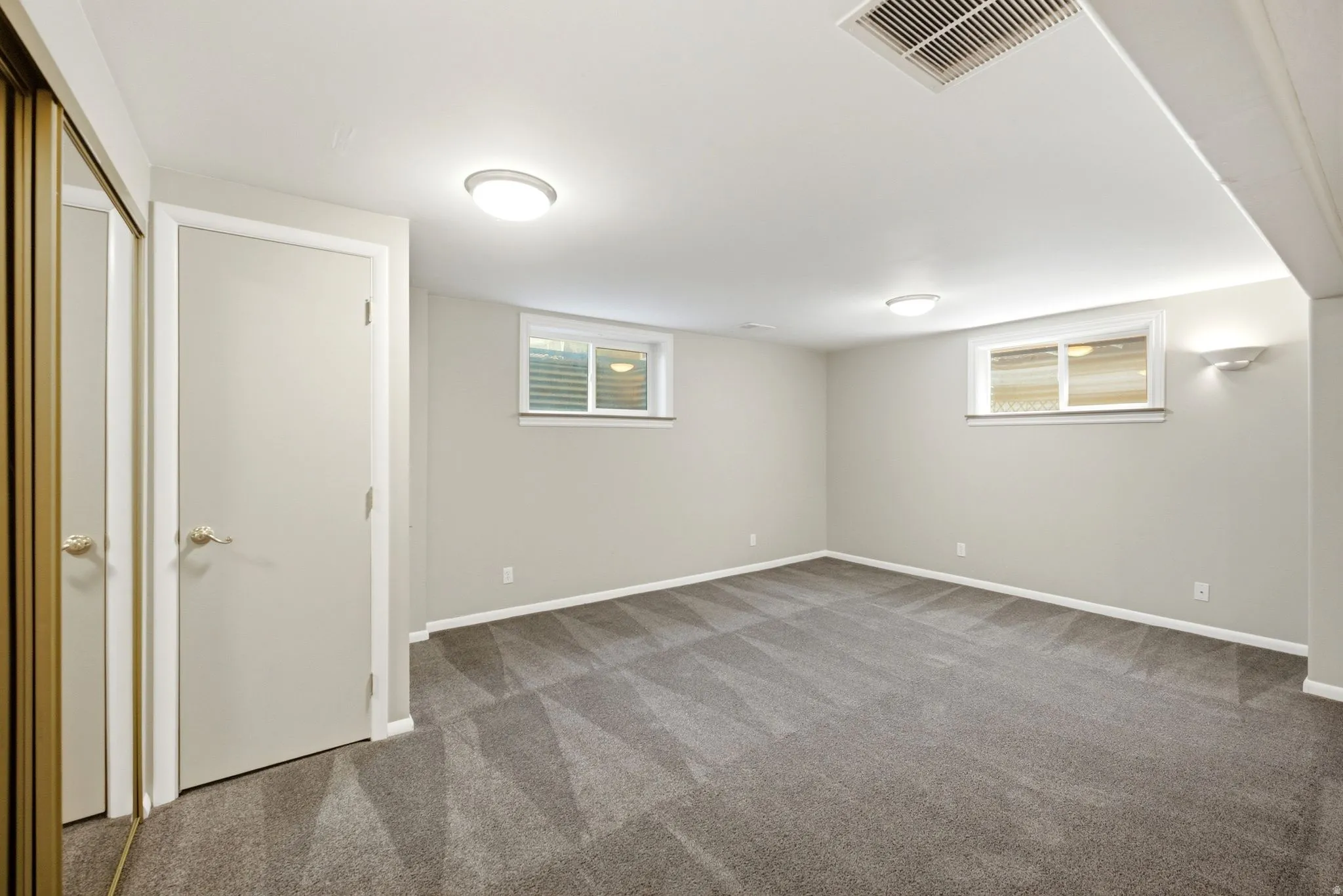 Spacious room featuring gray patterned carpet, light gray walls, and white trim