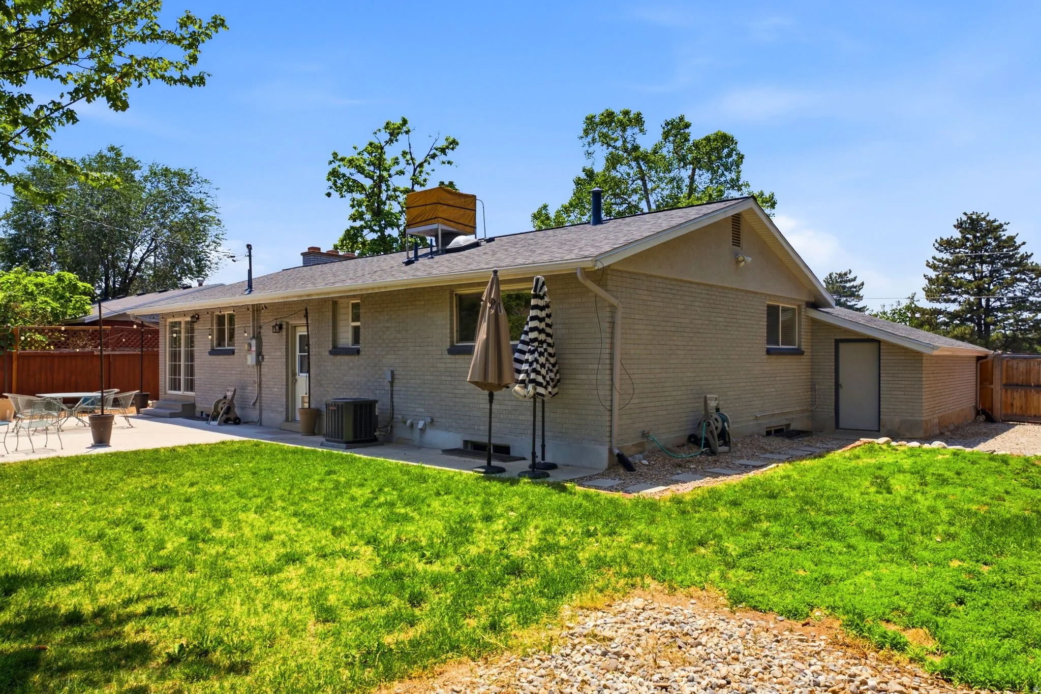 Expansive rear exterior featuring a concrete patio, brick facade, and a pitched shingle roof