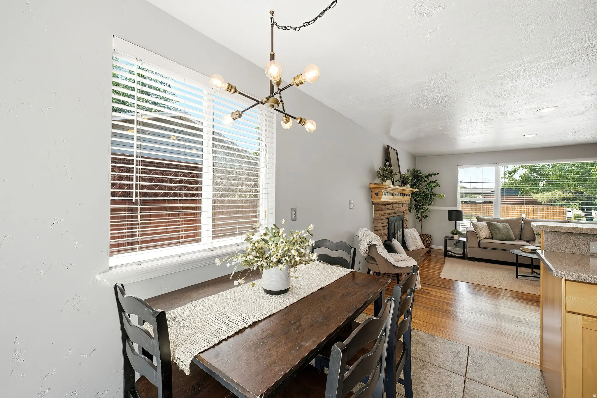 Dining area featuring a modern linear chandelier with exposed bulbs, white window blinds, and light gray wall paint