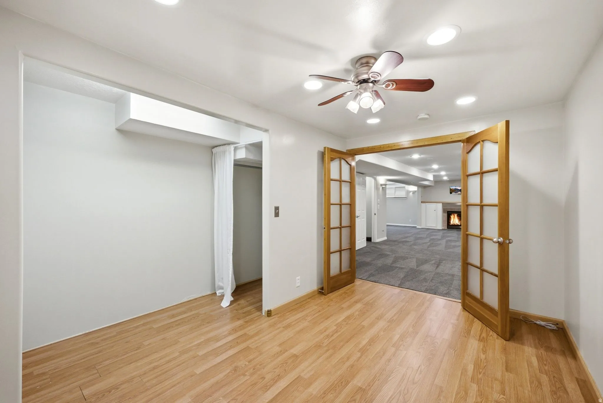 Wood-finish flooring throughout, featuring a ceiling fan with integrated lighting and recessed lighting
