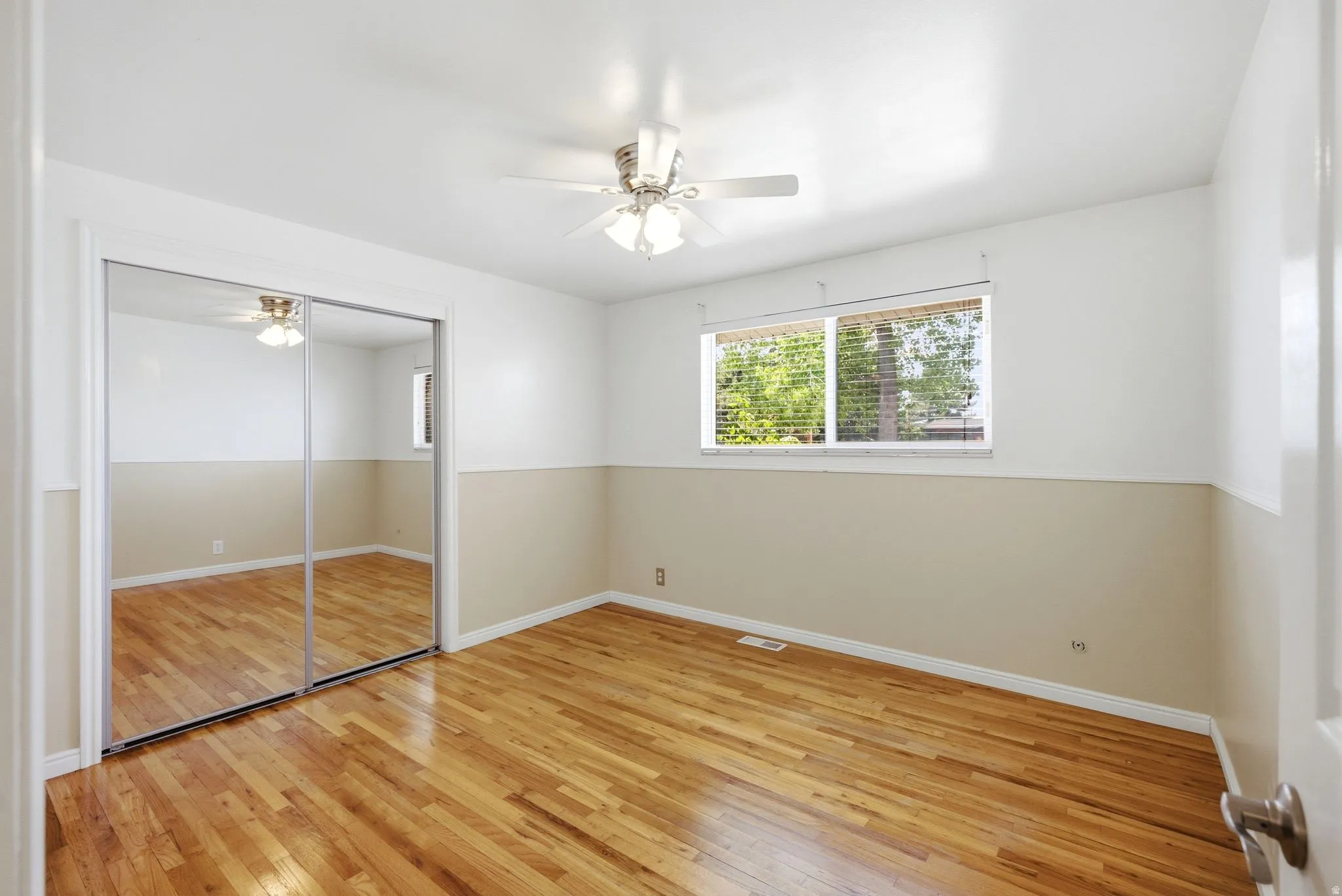 Room featuring wood-finish flooring and a ceiling fan with light fixture