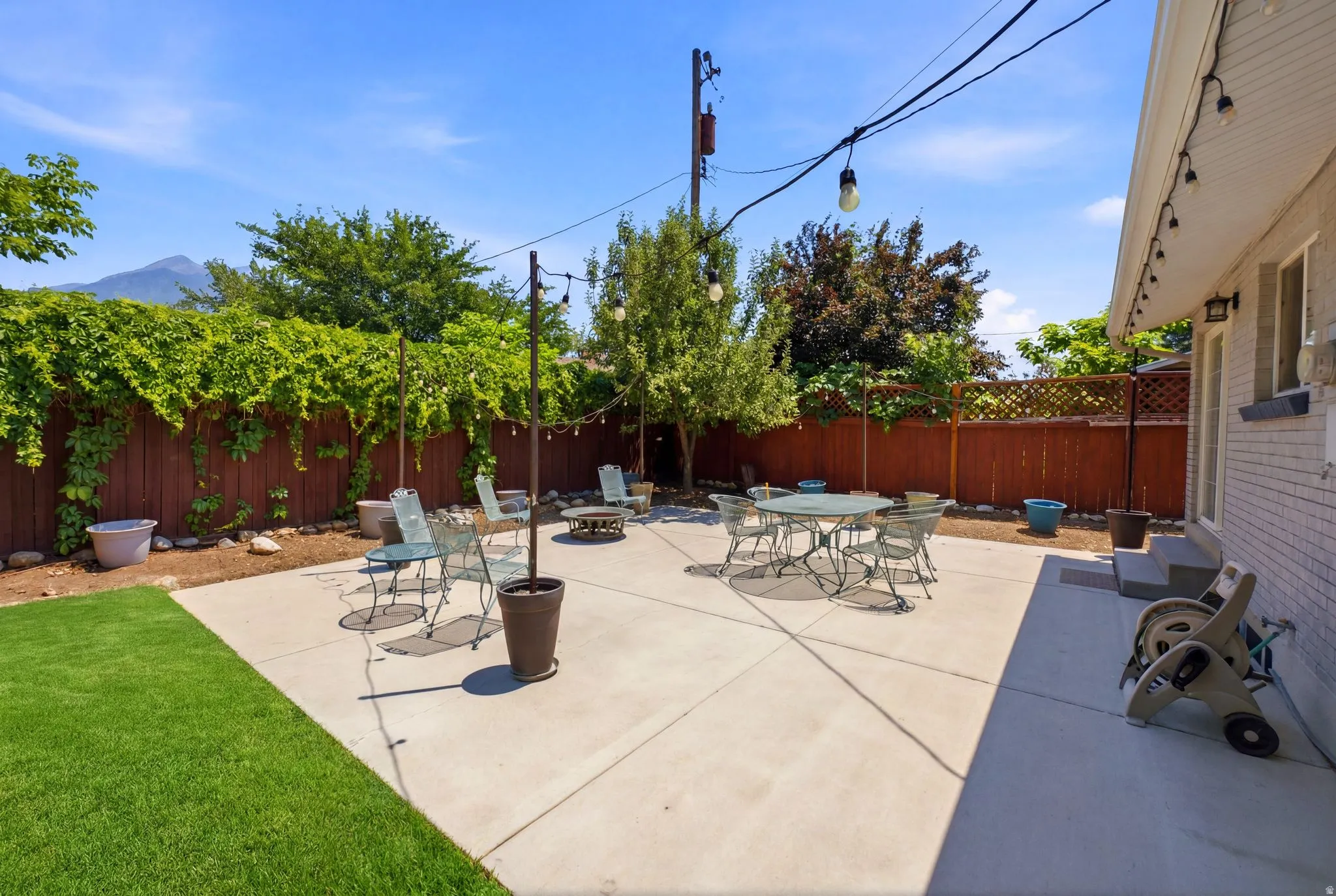 Spacious outdoor patio with concrete paving and a partial turf lawn