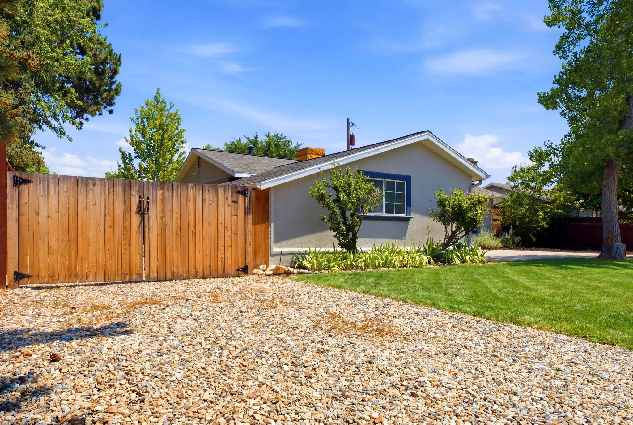 Gravel driveway leading to a wooden privacy gate with black hardware