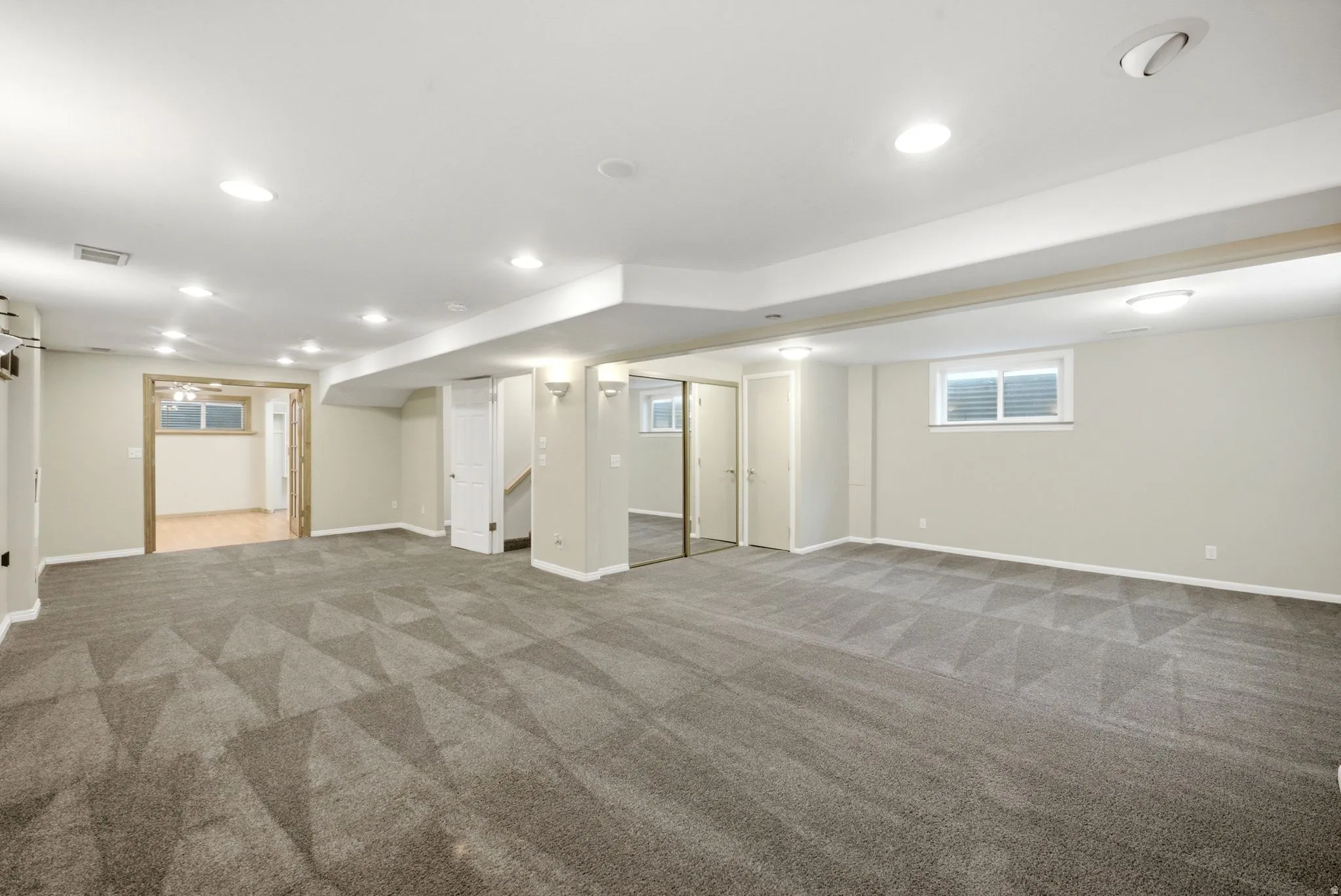 Spacious finished room featuring patterned carpeting, recessed lighting, and a neutral color palette