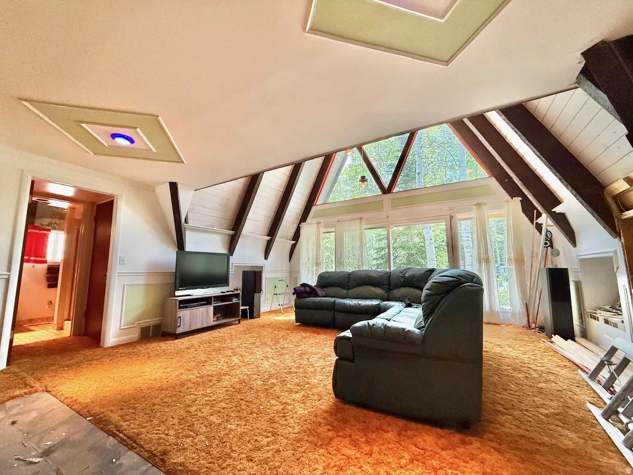 Vaulted ceiling with exposed beams and skylights complement the full wall of windows