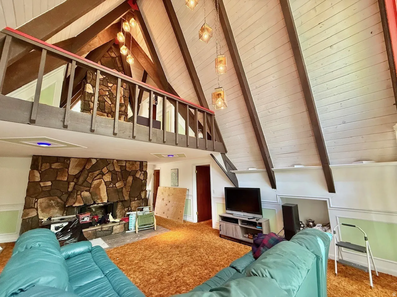 Vaulted ceiling living space featuring exposed wood beams and white paneled ceiling
