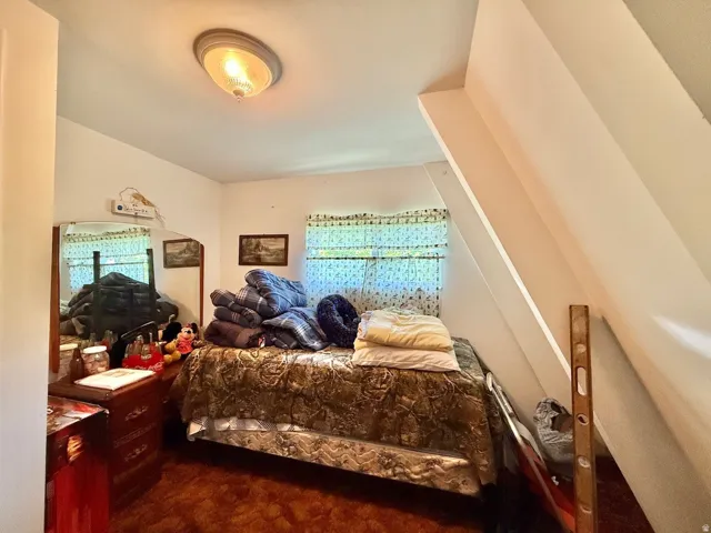 Room featuring a sloped ceiling, two windows with patterned curtains, and a flush-mount ceiling light fixture