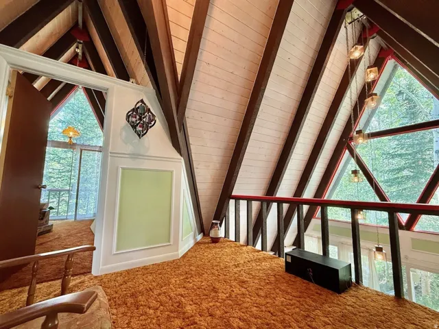 Vaulted wood-paneled ceilings with exposed beams, triangular window framing, and rich orange shag carpeting