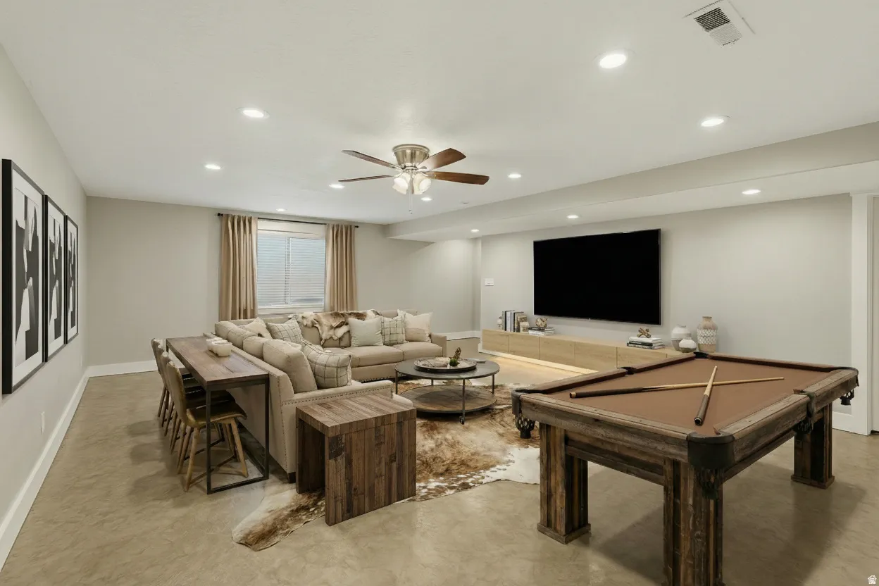 Spacious lower-level entertainment area featuring recessed lighting, high ceilings, neutral tones and a wet bar with mini fridge and room for a full size fridge