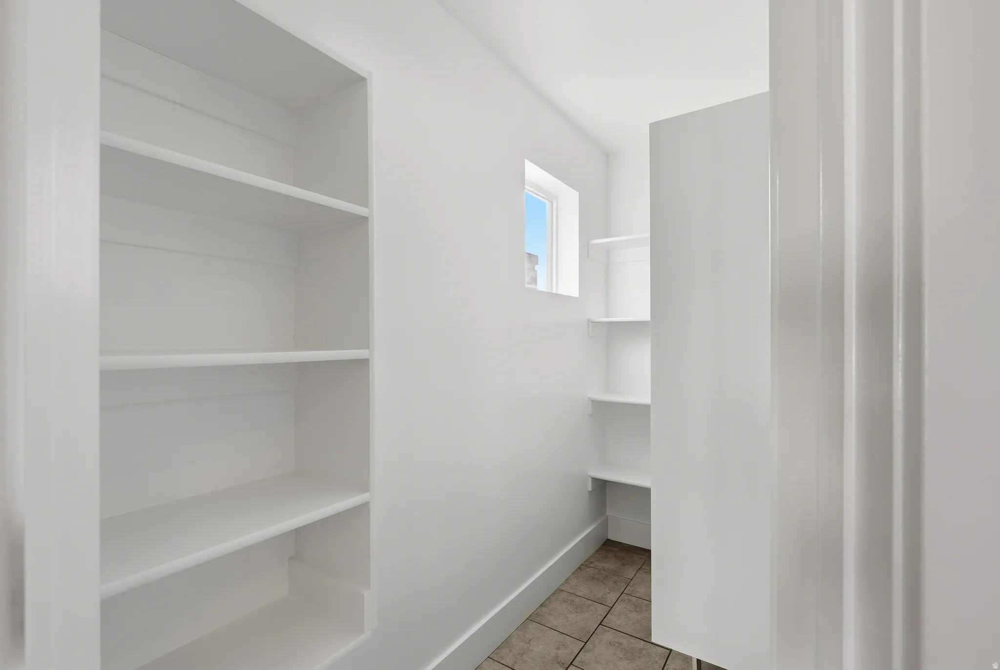Spacious walk-in pantry featuring extensive built-in shelving, a window