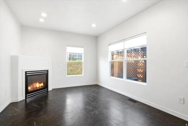 Living area featuring a corner fireplace, dark tile flooring, and multiple windows