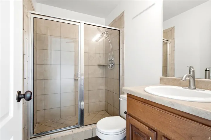 Bathroom featuring a glass-enclosed shower with subway tile surround, a single vanity with a light-colored countertop, and a built-in medicine cabinet