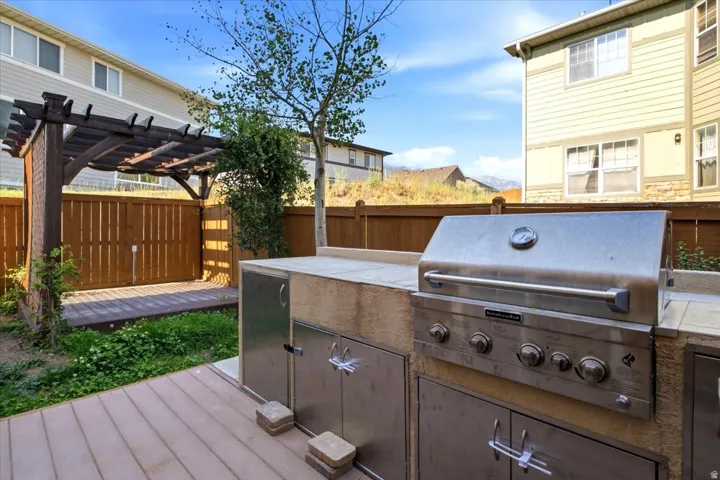 Outdoor kitchen featuring a built-in stainless steel grill, integrated storage, and a tiled countertop