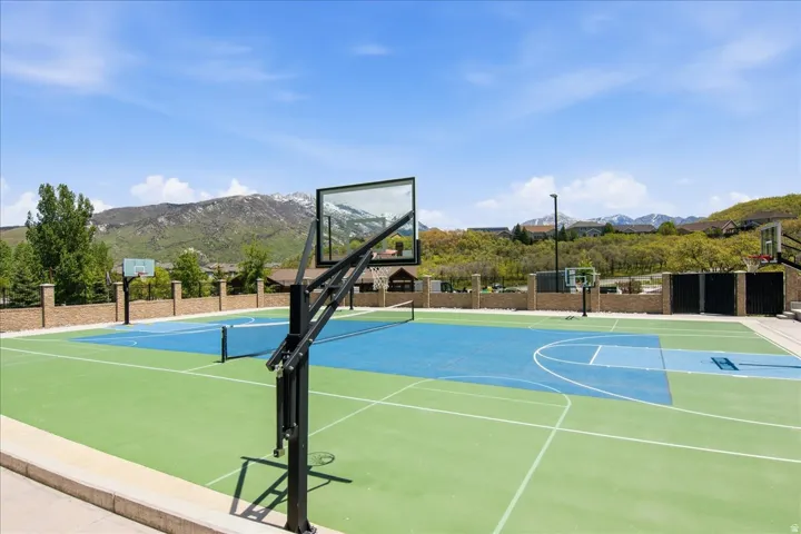 Multi-sport court featuring green and blue surfacing, multiple basketball hoops, and a tennis net
