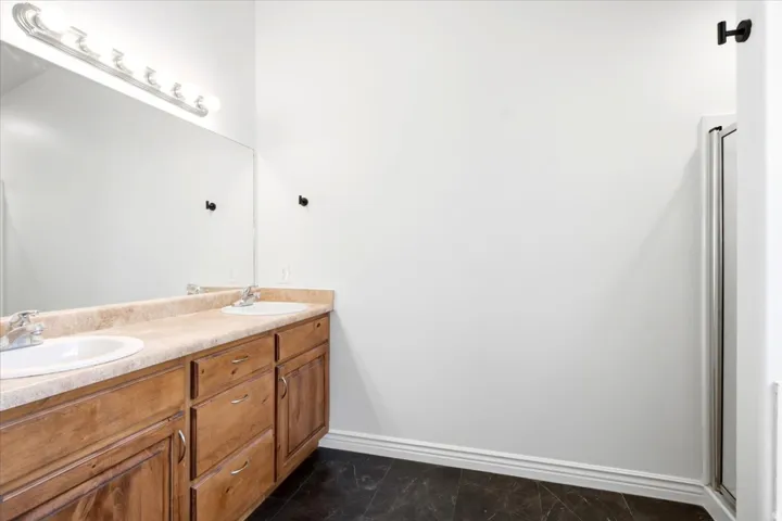 Dual vanity with wood-finish cabinetry, light-toned countertop, and undermount sinks
