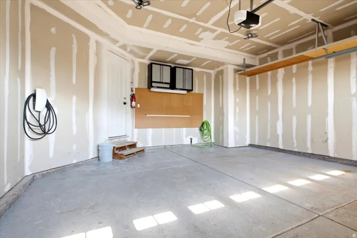Spacious garage with an epoxy-coated floor, overhead storage shelving, and a built-in electric vehicle charging station