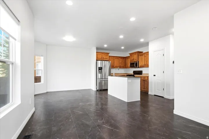 Modern kitchen with wood cabinetry, stainless steel refrigerator, and recessed lighting