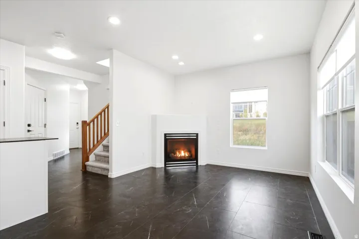 Living area featuring dark tile flooring, a built-in fireplace with a minimalist surround, recessed lighting, and multiple windows