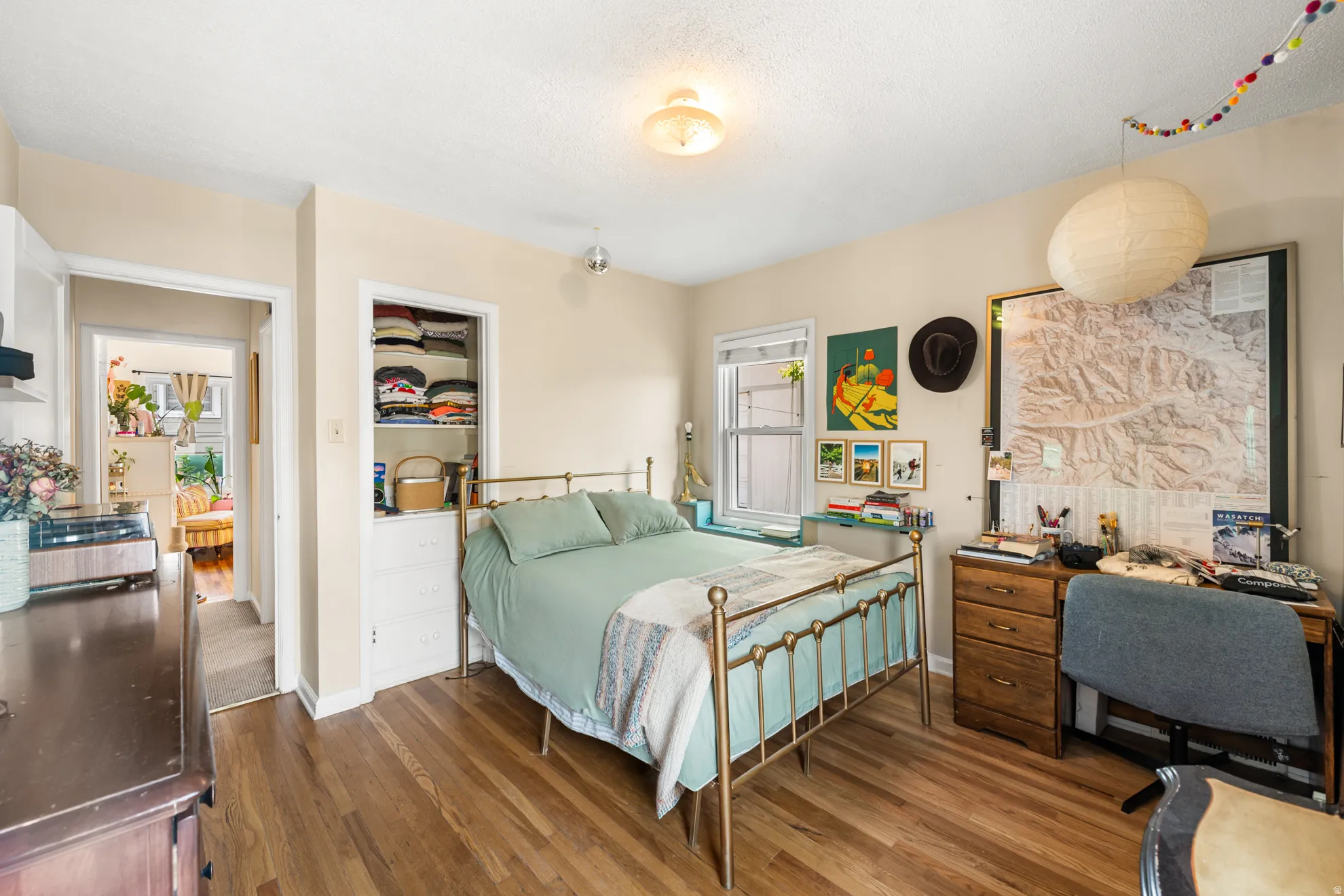 Room featuring warm wood-finish flooring and a built-in closet with shelving