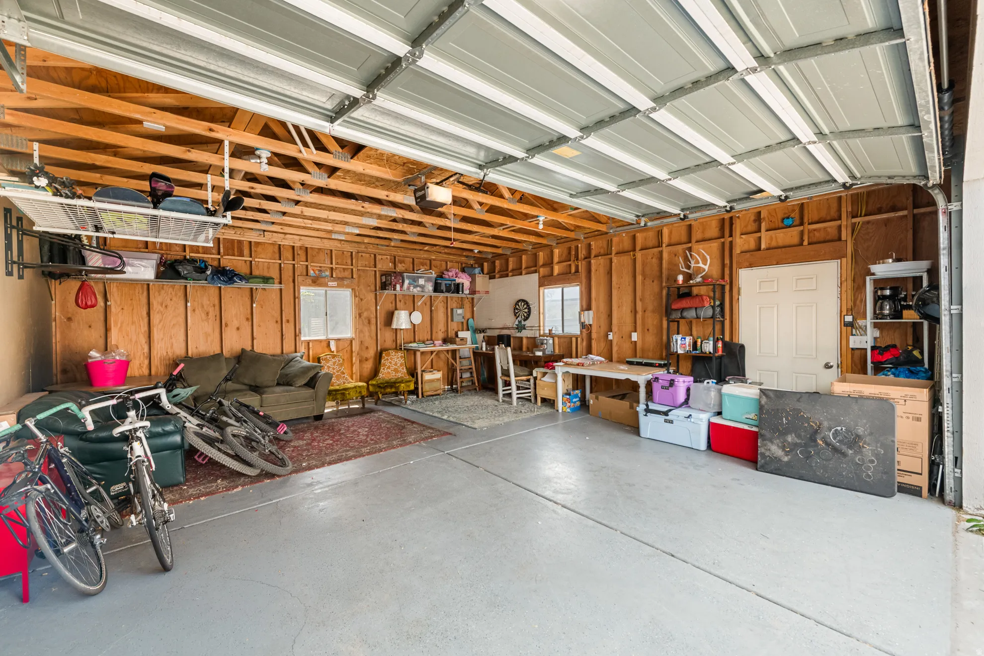 Spacious garage featuring a light gray concrete floor and exposed wooden stud walls