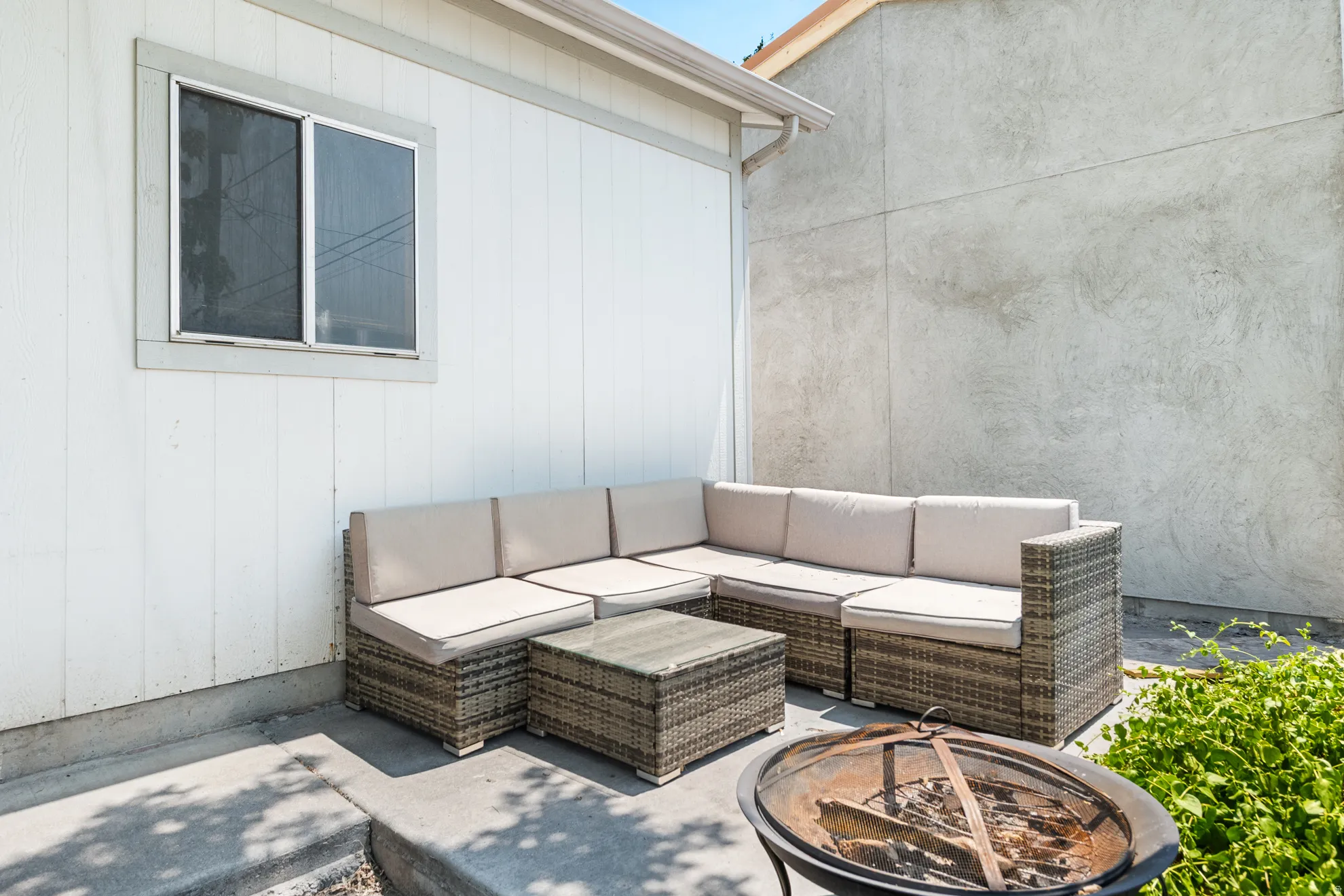 Private concrete patio featuring perimeter landscaping and a window with trim detail