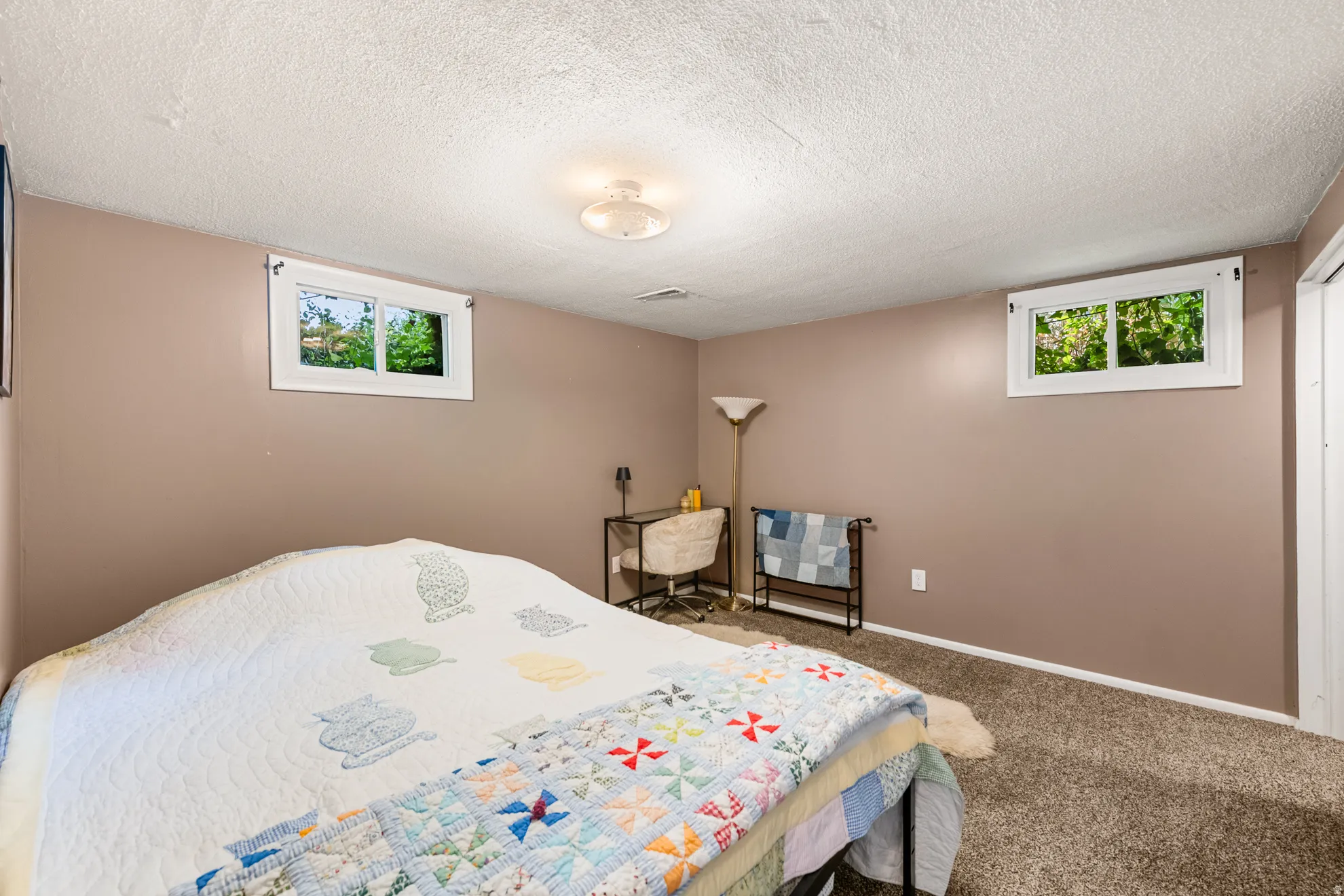Carpeted room featuring two egress windows, light-toned walls, and a white ceiling with a flush-mount light fixture