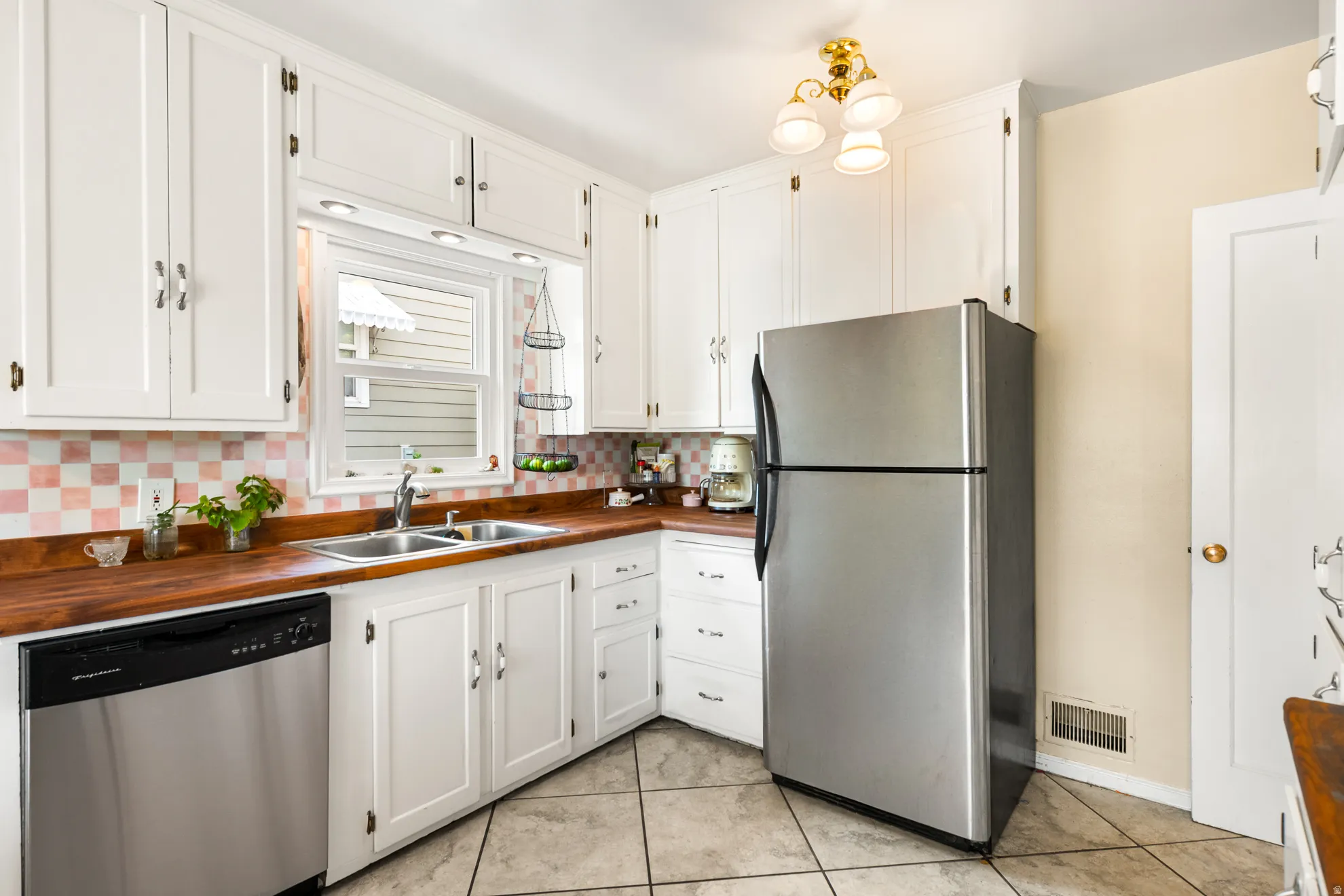 Kitchen featuring white cabinetry, wood-finish countertops, and a dual basin stainless steel sink