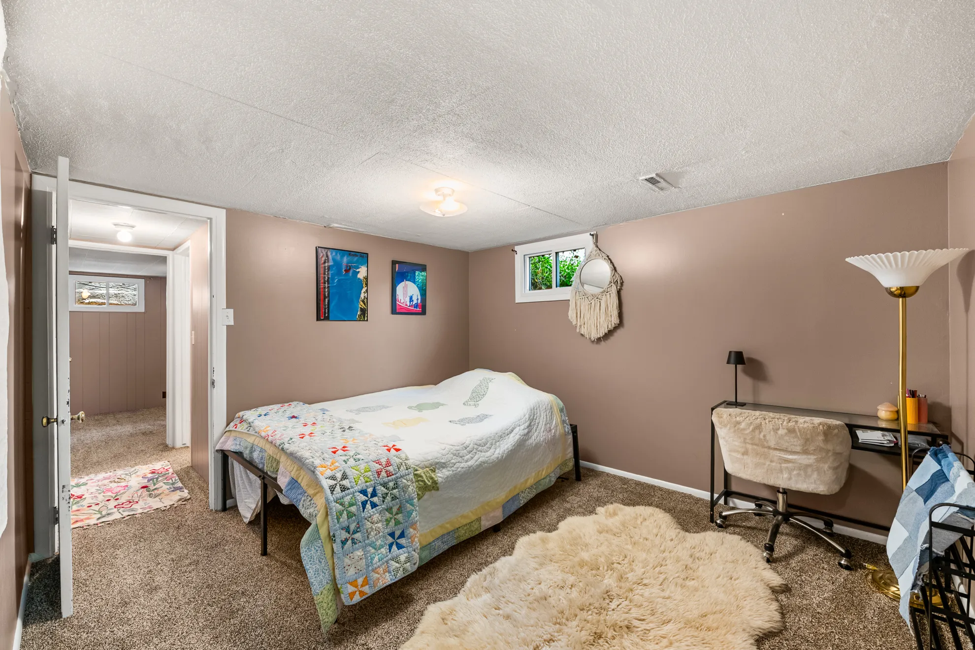 Spacious room featuring neutral-toned walls, textured ceiling, and a window providing natural light