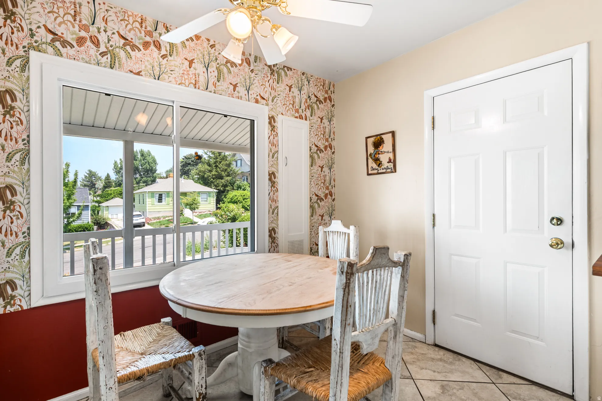 Eat-in kitchen area featuring a large window, patterned wallpaper, tile flooring, and a ceiling fan with integrated lighting