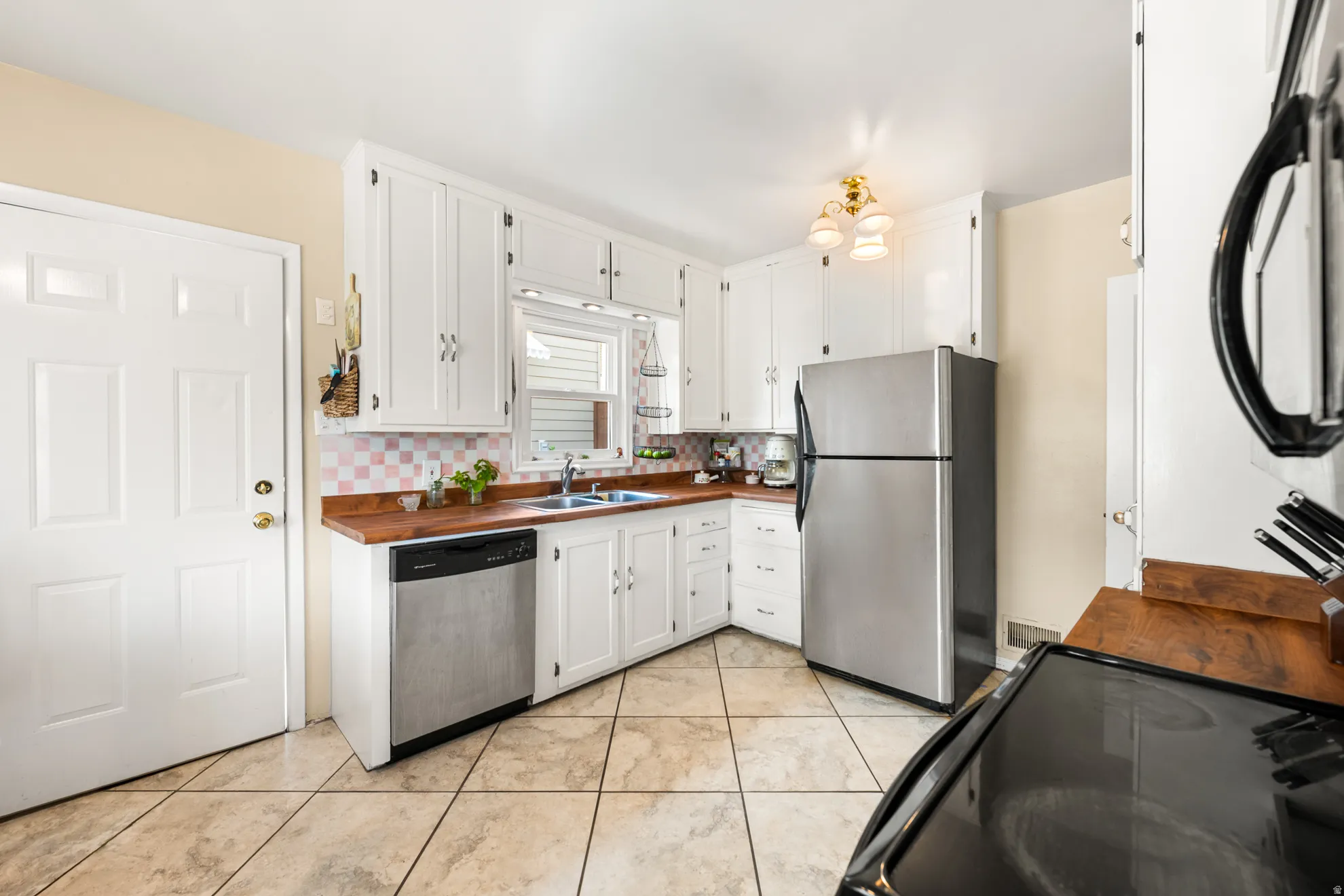 Kitchen featuring white cabinetry, wood-finish countertops, stainless steel appliances, and tile flooring