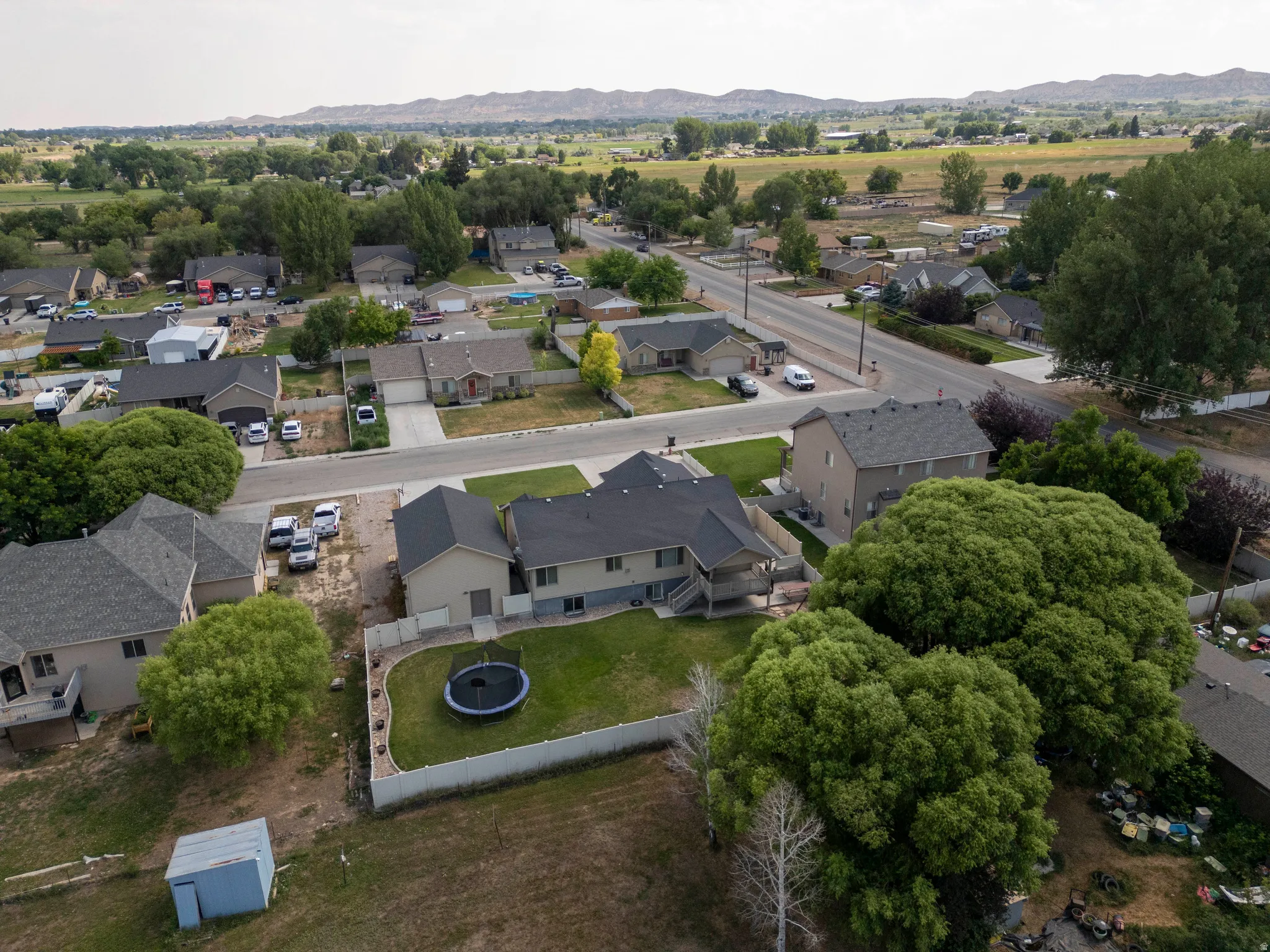 Spacious rear yard featuring an expansive lawn, mature perimeter trees, and a privacy fence