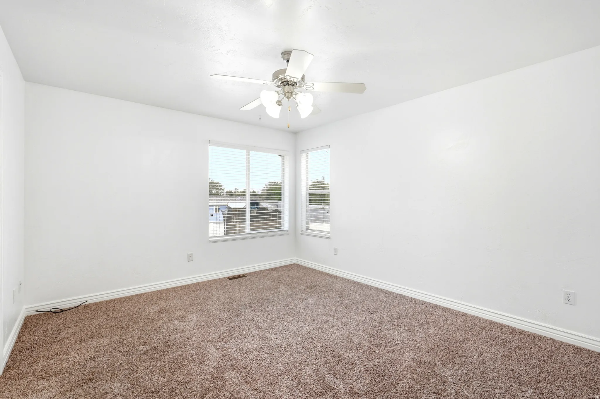 Carpeted room featuring a ceiling fan with integrated lighting, white walls, and a window with blinds