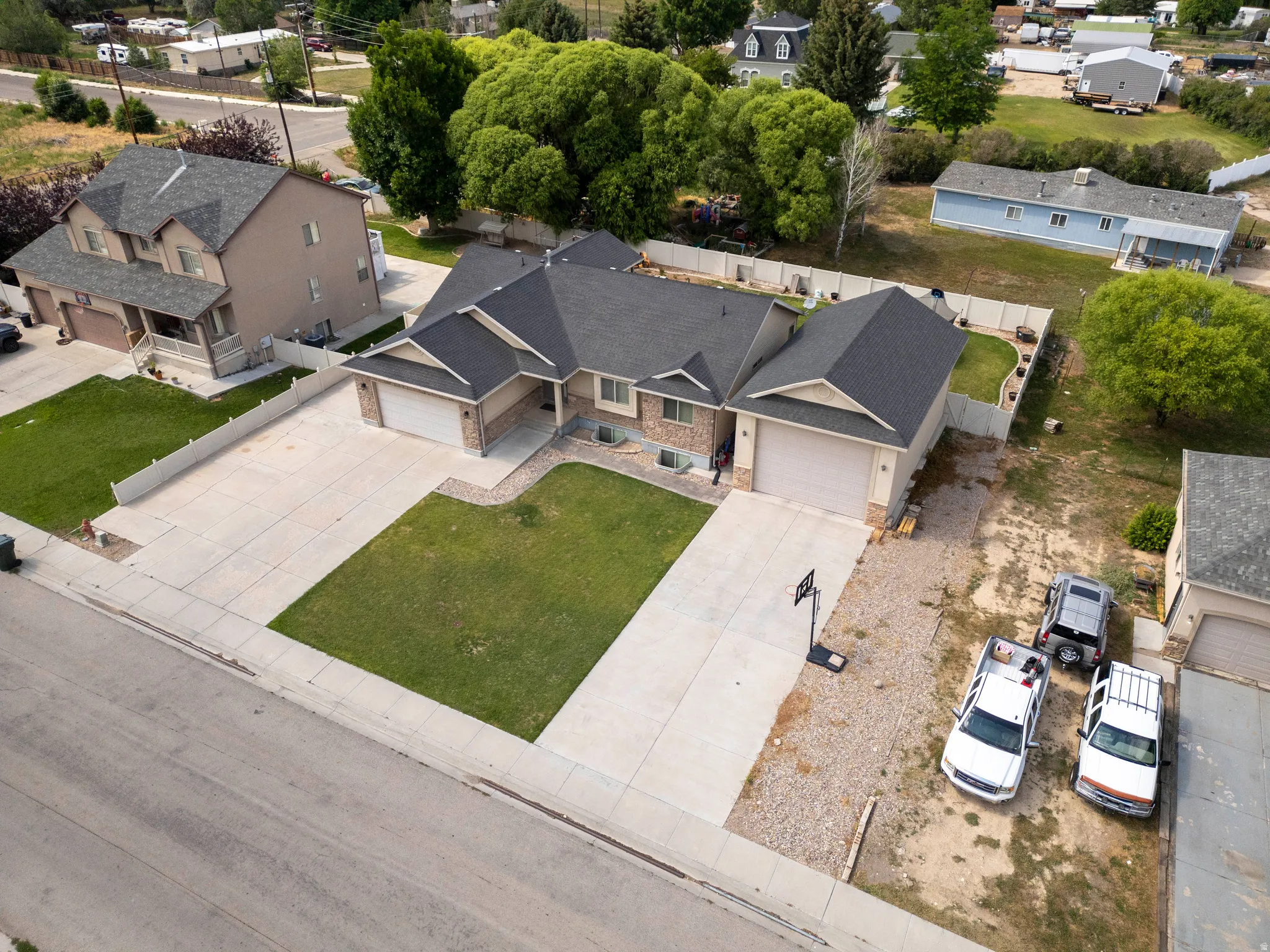 Expansive concrete driveway with a basketball hoop, leading to a two-car garage