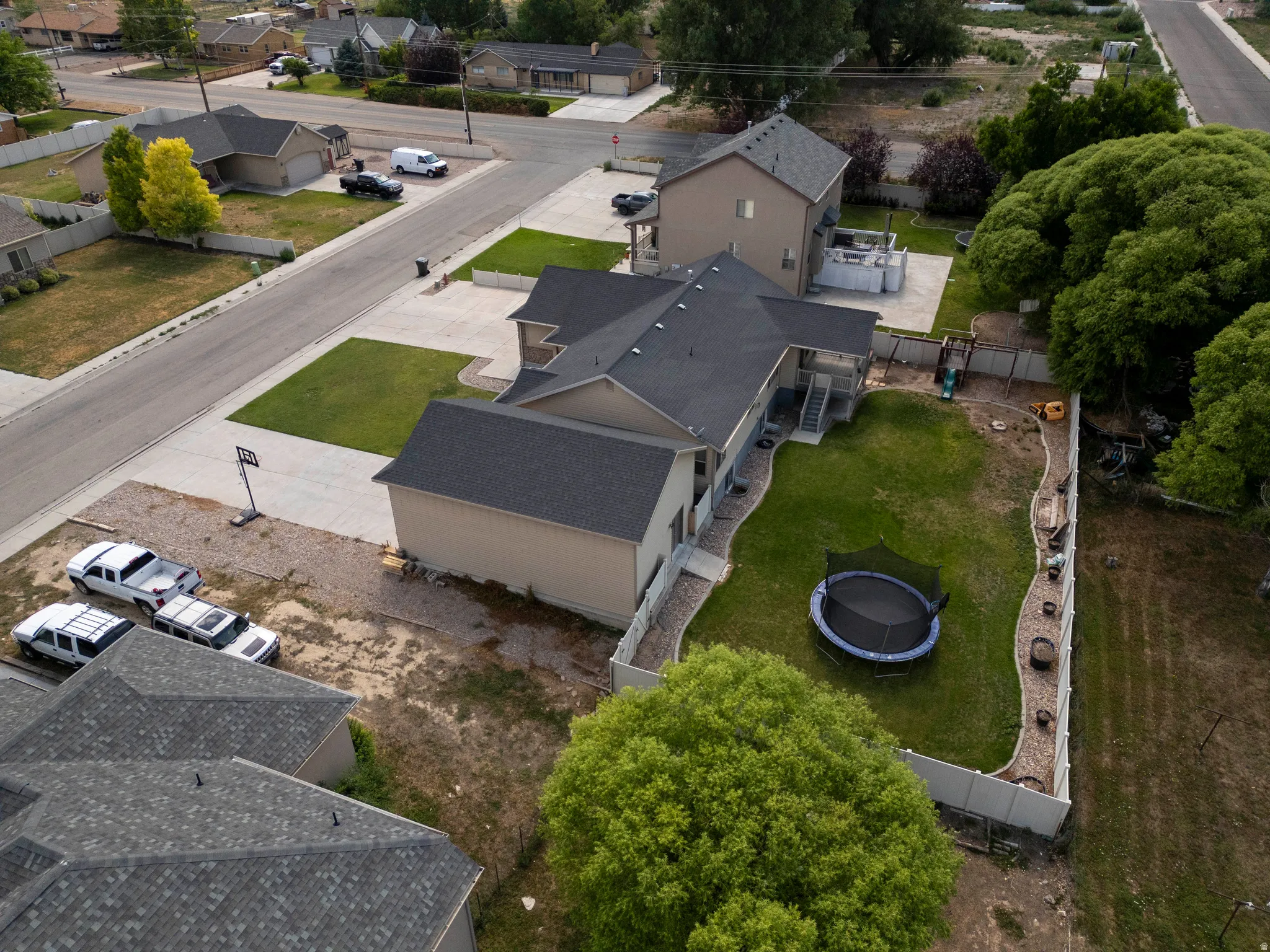 Expansive backyard featuring a manicured lawn, perimeter fencing, and mature trees