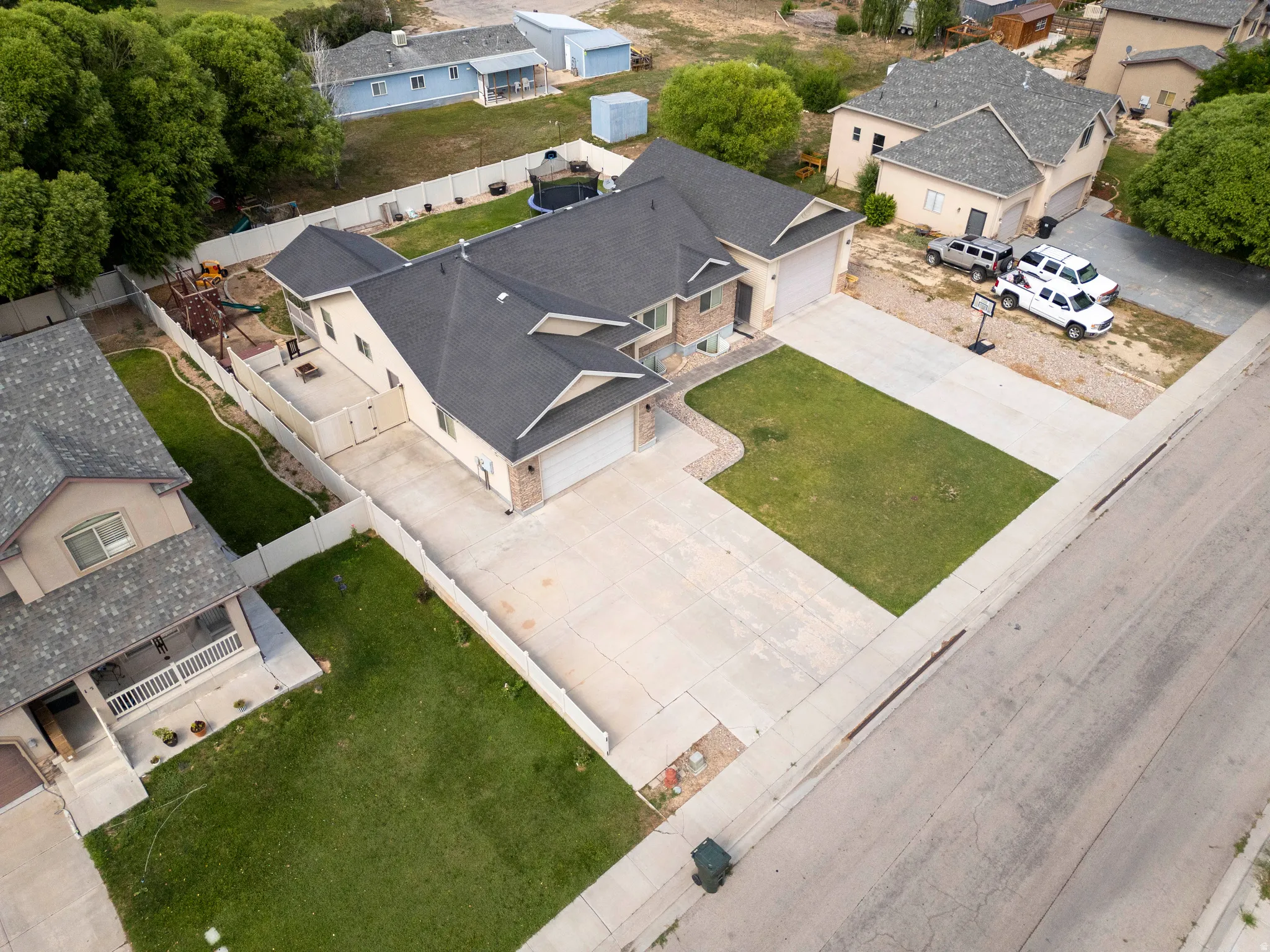 Exterior with a dark shingle roof and light-colored siding, featuring an attached garage, paved driveway, and established lawn