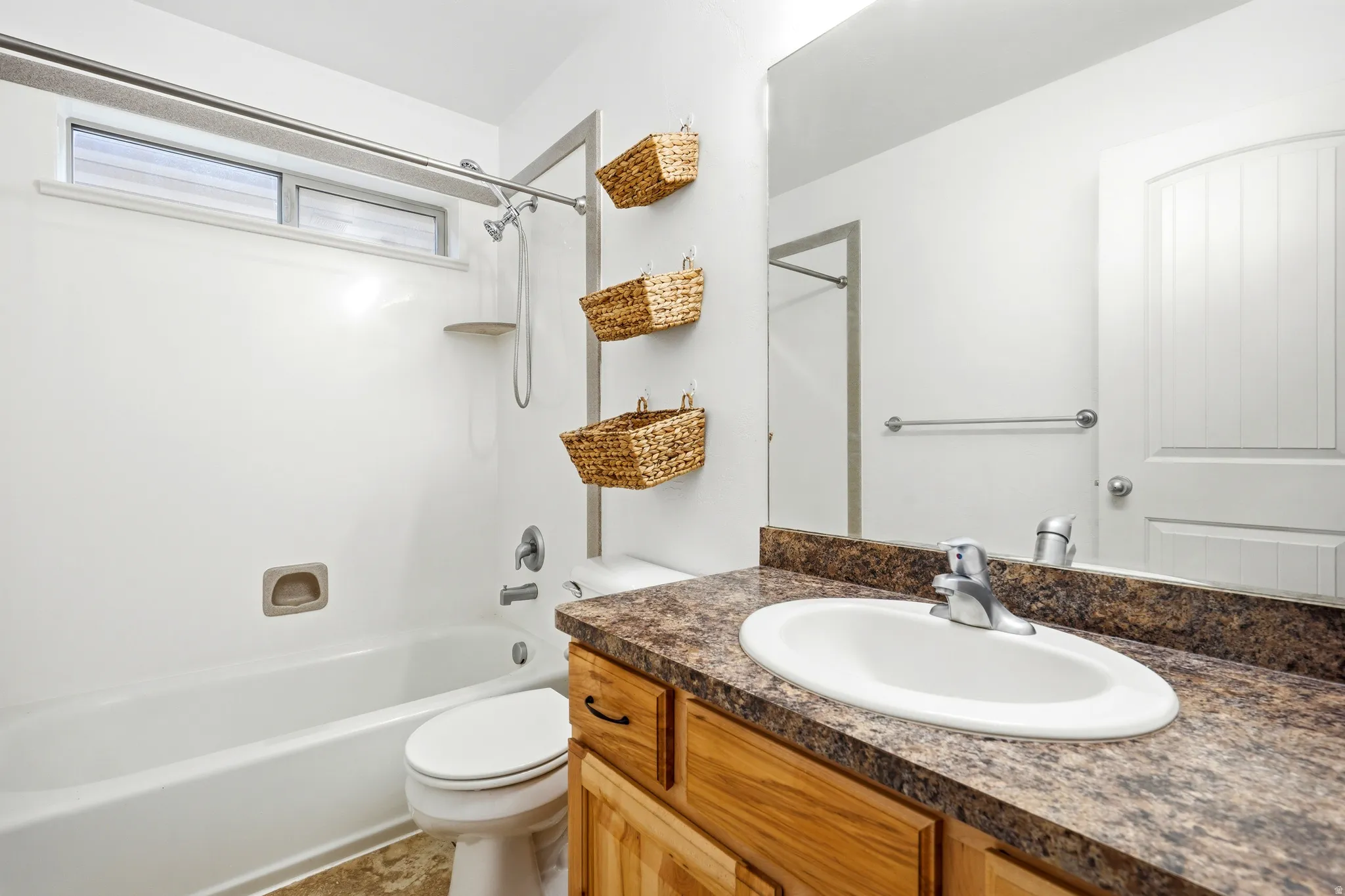 Bathroom featuring a single vanity with a laminate countertop, integrated sink, and an expansive wall-mounted mirror