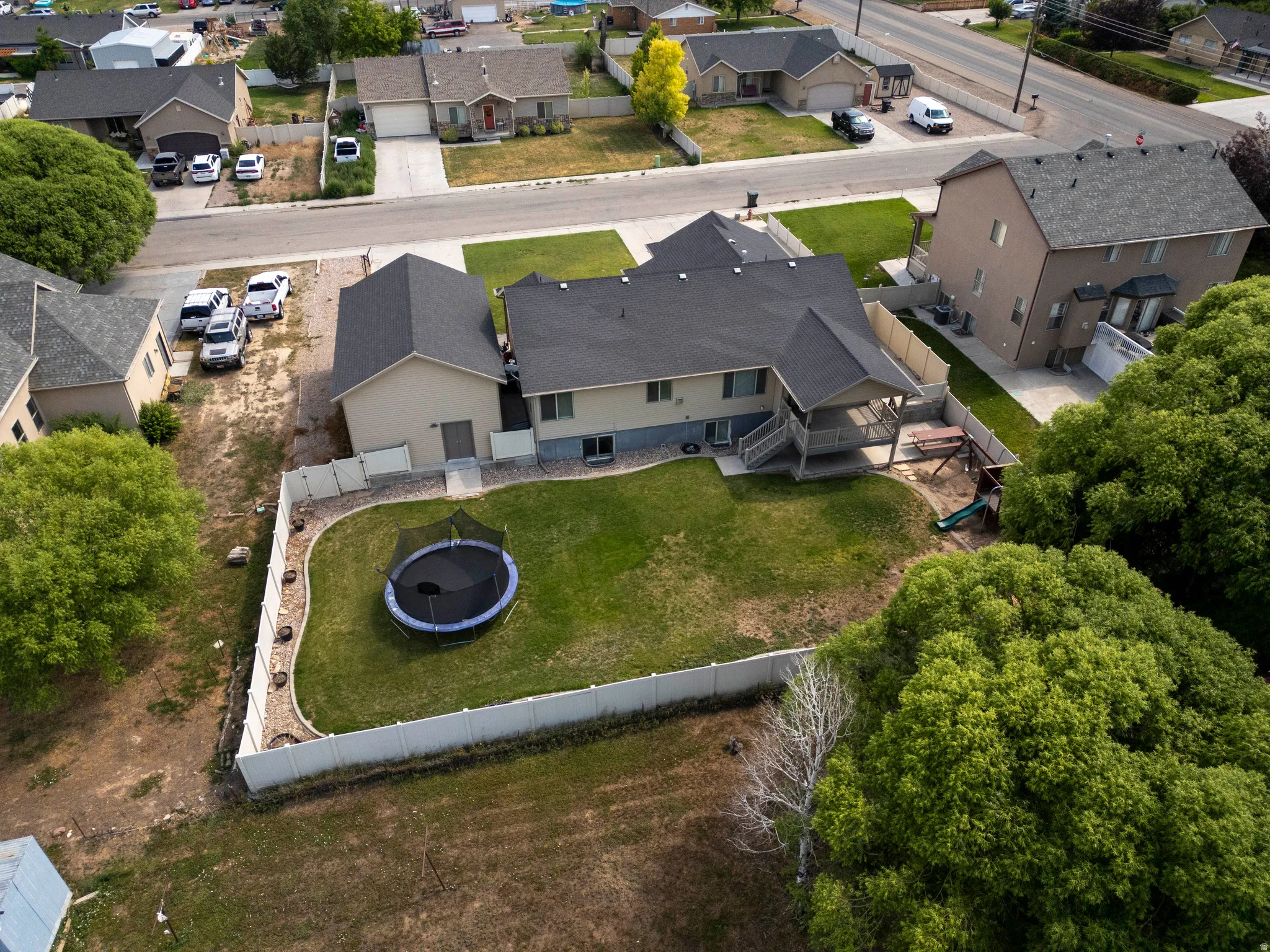Expansive backyard featuring a manicured lawn, full privacy fencing, and a covered back deck