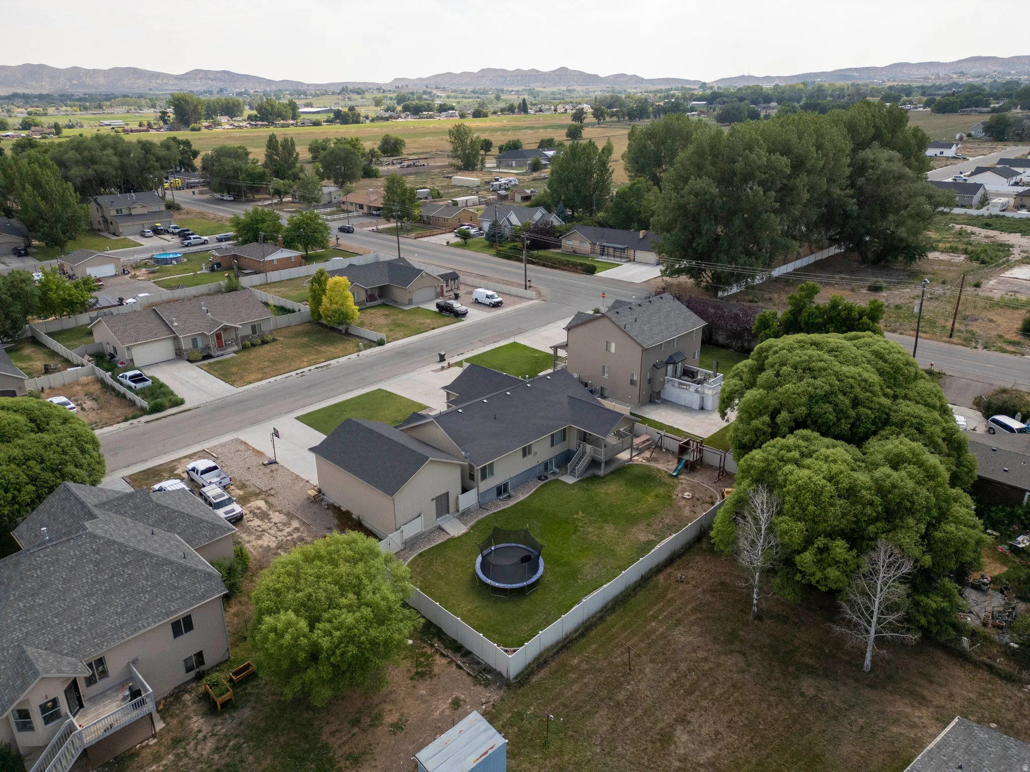 Expansive residential property featuring a large backyard with a white privacy fence and mature trees