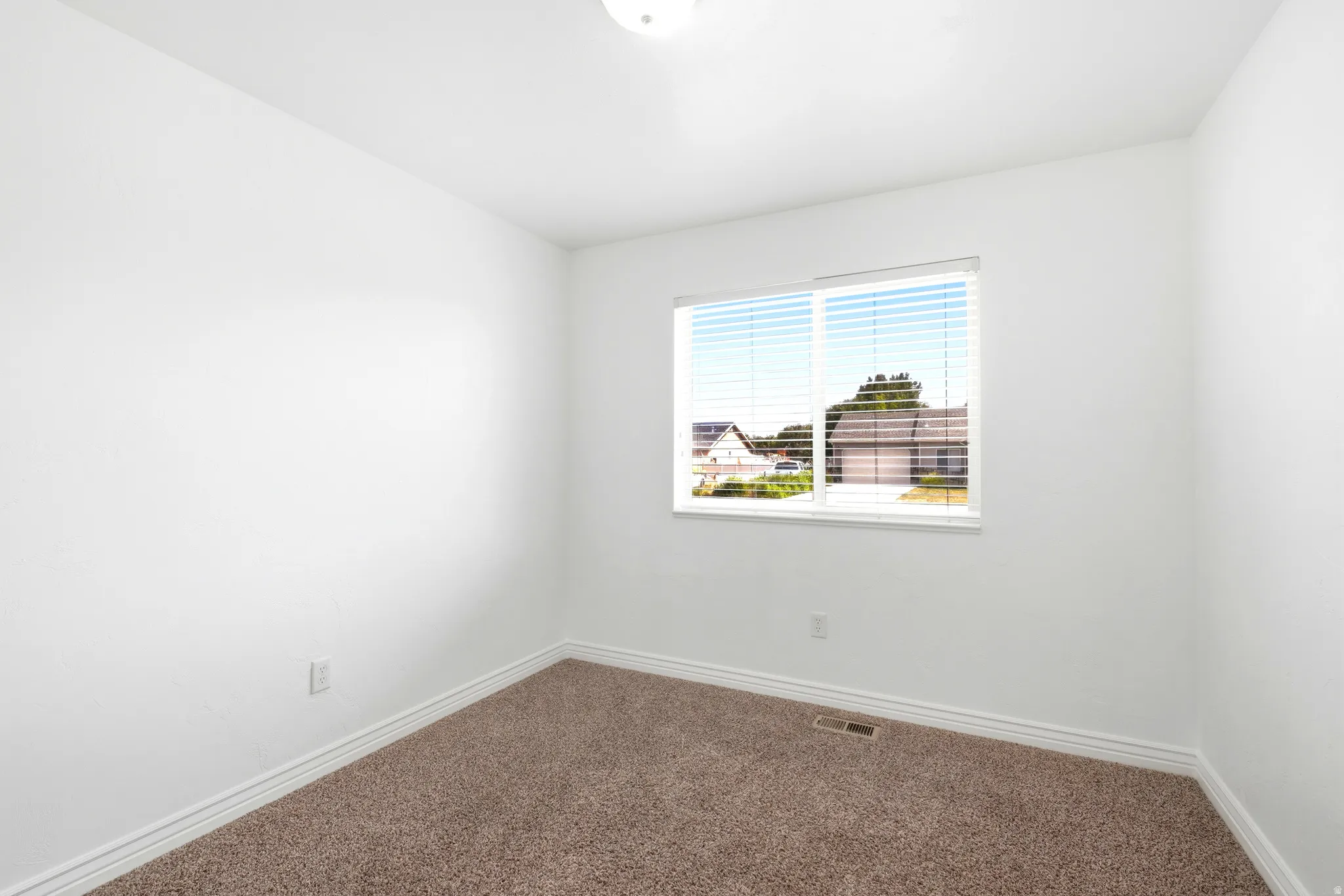 Carpeted interior space featuring white walls, a white ceiling, and white baseboards