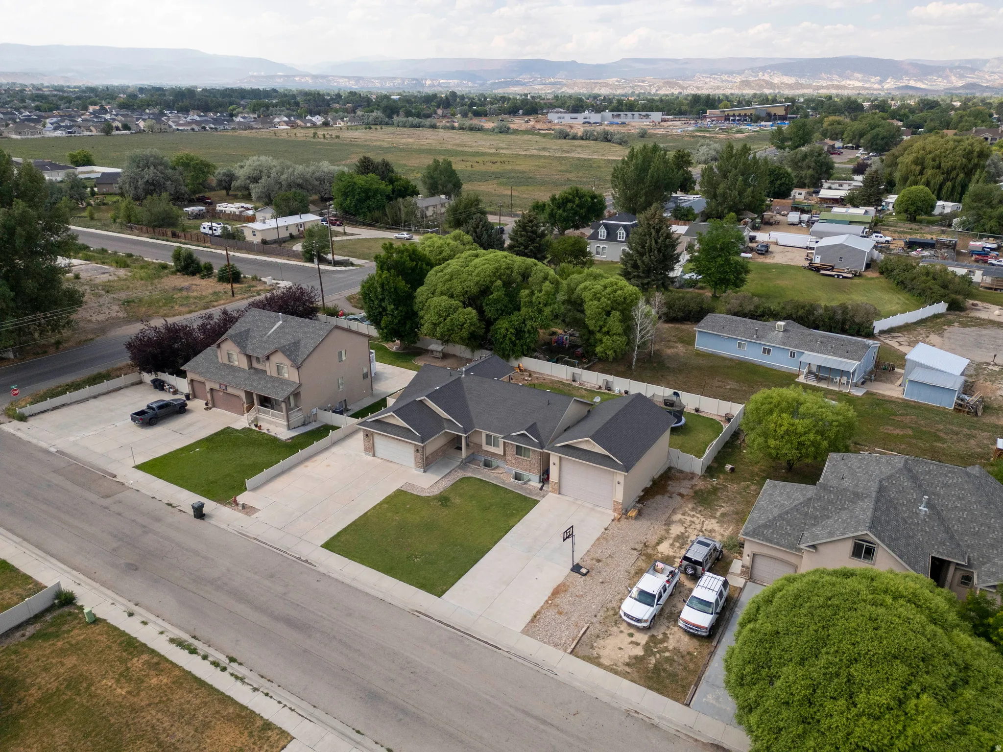 Residential property featuring a two-story home with an attached garage, a single-story home with an attached garage, and a single-story light blue home
