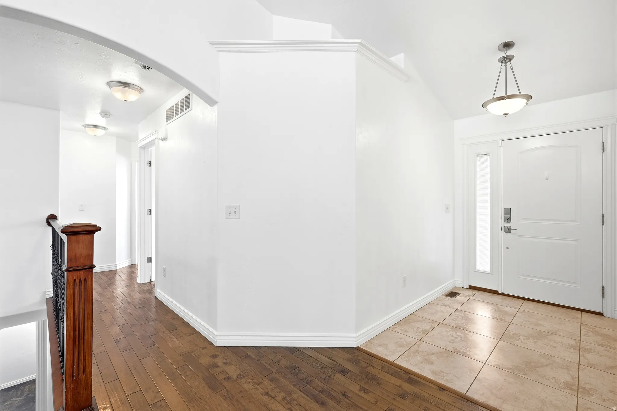 Entryway featuring a white paneled door with a sidelight, a decorative pendant light, and neutral-toned tile flooring