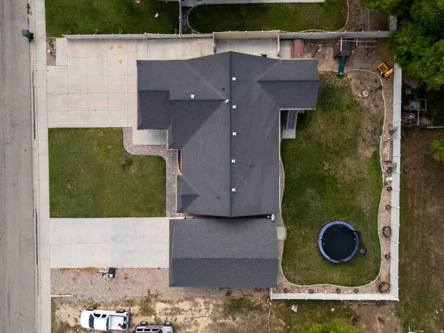 Expansive property with a dark shingle roof and a spacious concrete driveway