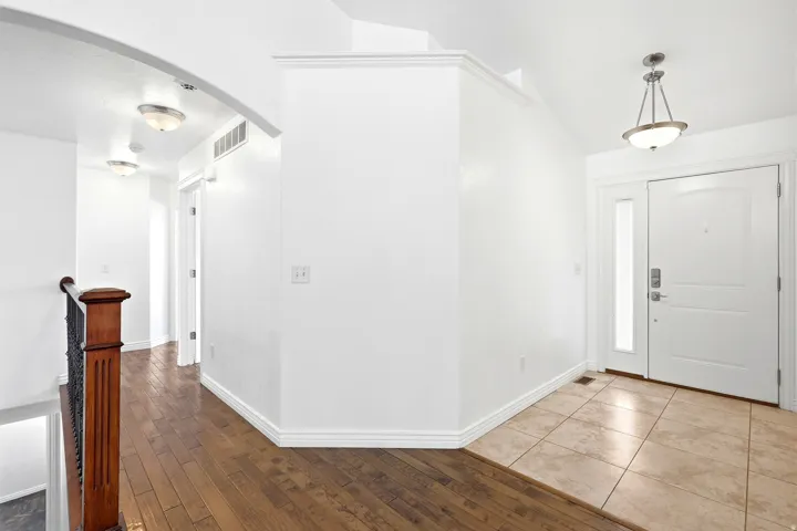 Entryway featuring a white paneled door with a sidelight, a decorative pendant light, and neutral-toned tile flooring