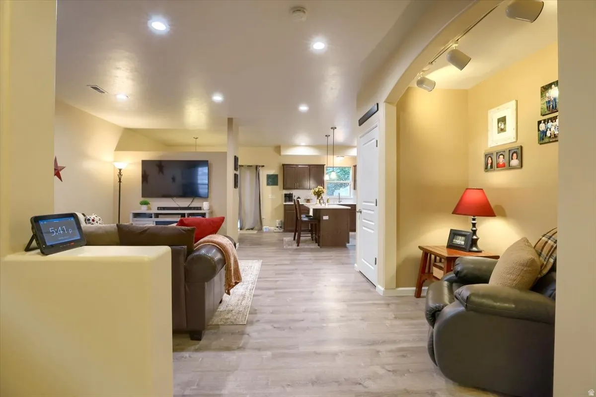 Spacious open-concept living area featuring wood-finish flooring, recessed lighting, and an arched entryway