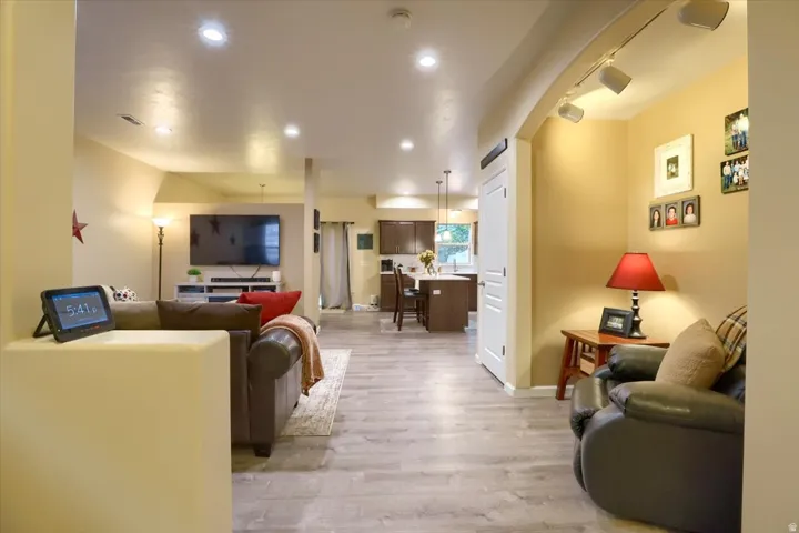 Spacious open-concept living area featuring wood-finish flooring, recessed lighting, and an arched entryway